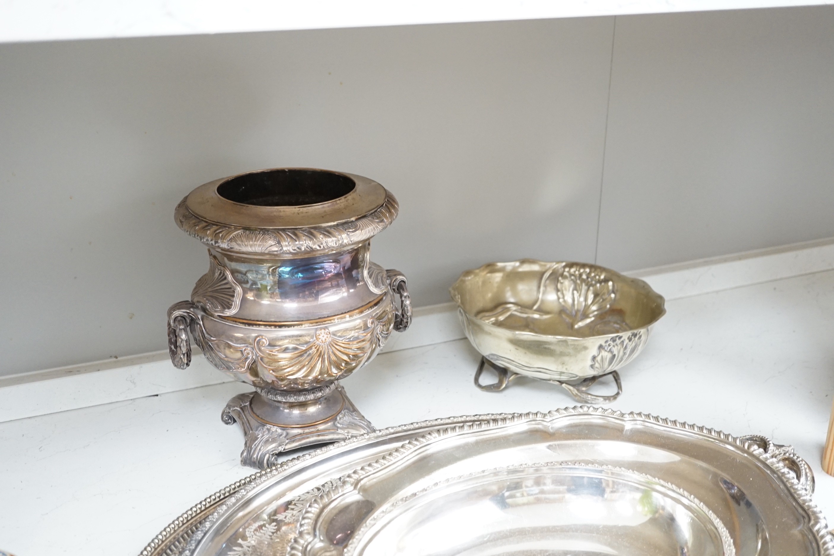 Ten silver plated items, including six good trays, a wine cooler, an Art Nouveau bowl raised on 3 feet, tray of drinking vessels, and a toast rack, largest tray 68cm